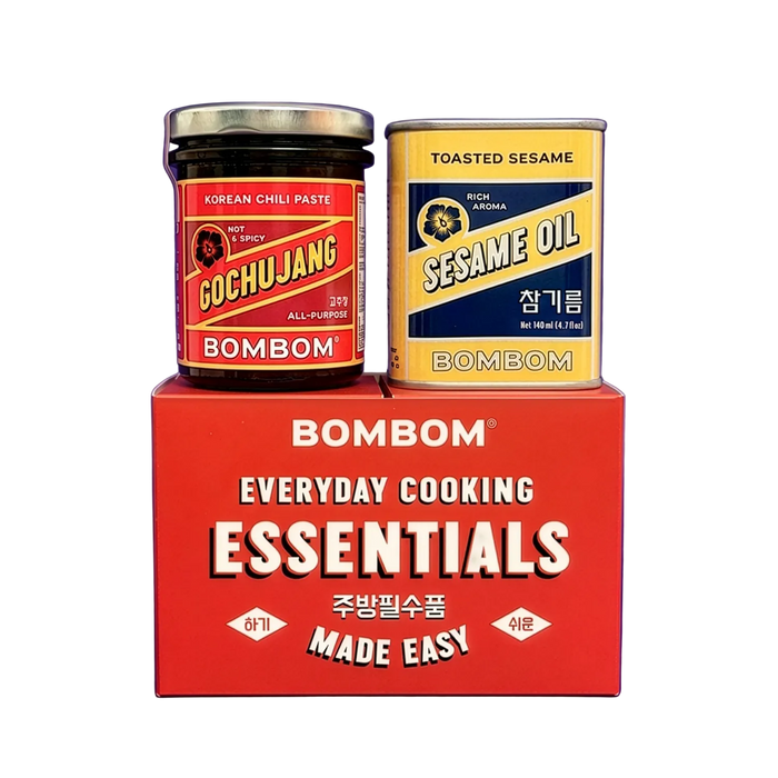 A red BOMBOM Everyday Cooking Essentials box holding two BOMBOM products: a glass jar of Korean Chili Paste and a tin of Sesame Oil, on a white background.